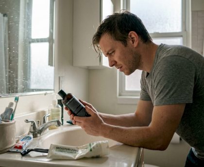 Man reading detox shampoo instructions bathroom
