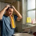 Man shampooing hair in everyday apartment bathroom