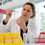 Technician extracting hair sample in forensic lab