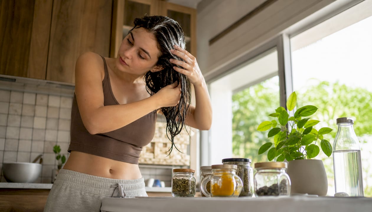 Woman applying detox shampoo in bathroom