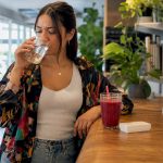 Woman drinking detox drink at kitchen table