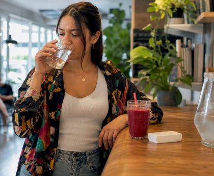 Woman drinking detox drink at kitchen table