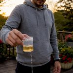 Person collecting urine sample in bathroom