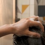 Hands applying shampoo to hair over sink