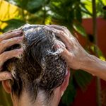 Hands applying clarifying shampoo to hair