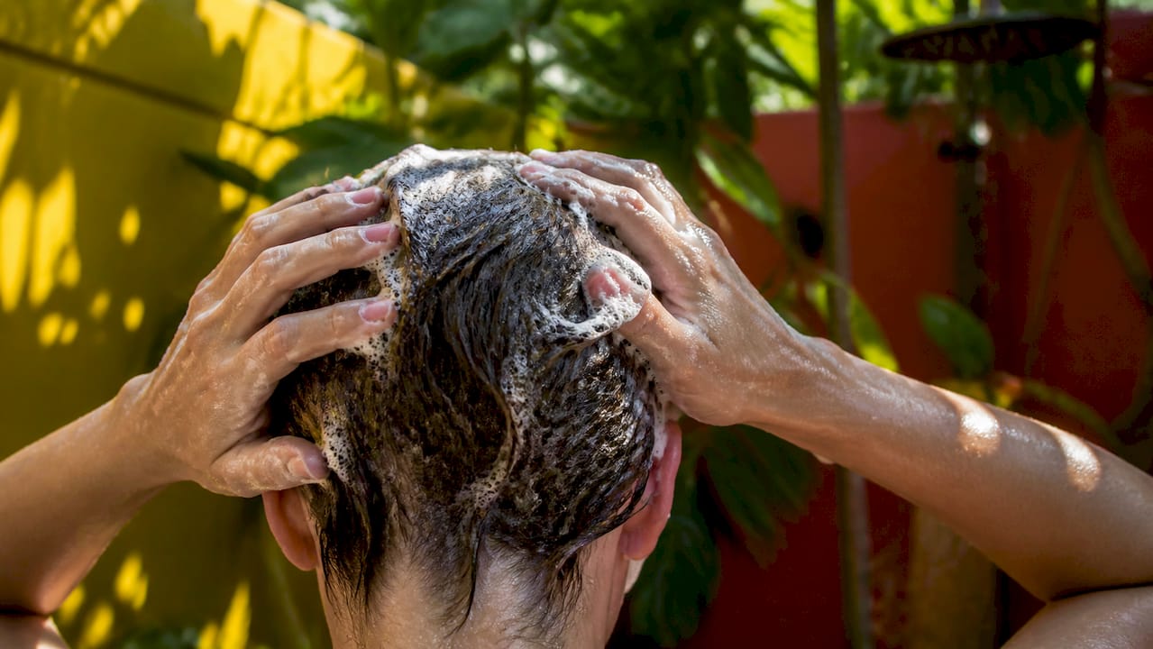 Hands applying clarifying shampoo to hair