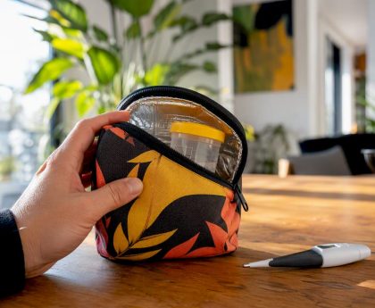 Hand holding insulated pouch with urine cup