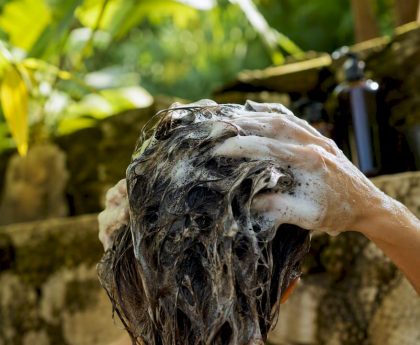 Hands applying clarifying shampoo to hair scalp
