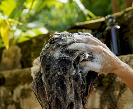 Hands applying clarifying shampoo to hair scalp