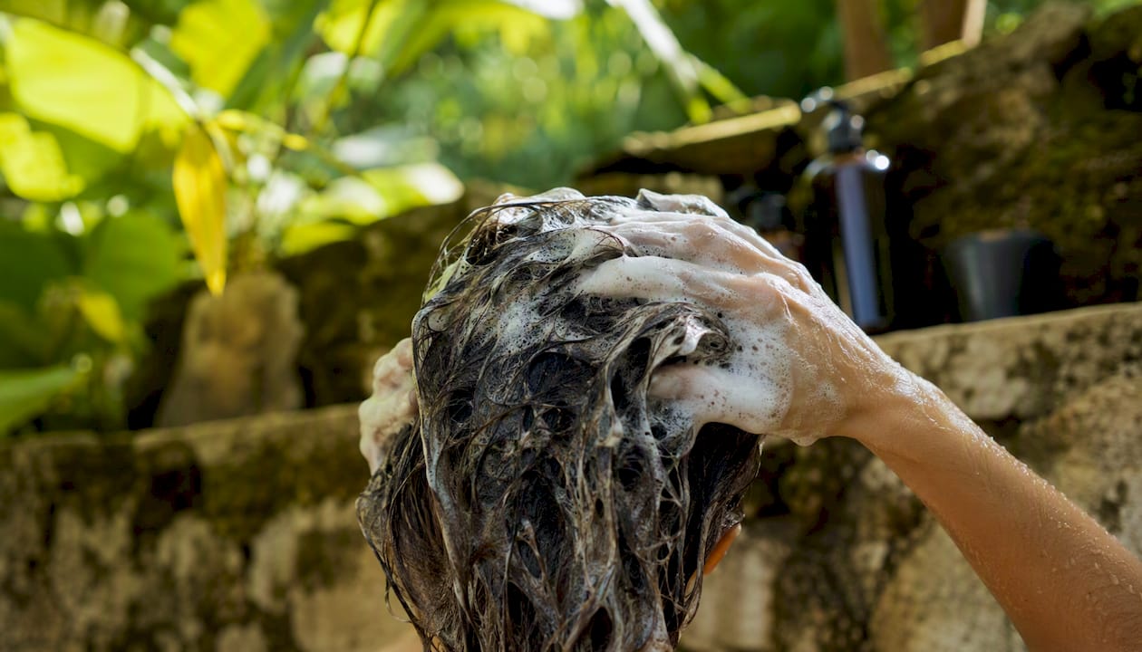 Hands applying clarifying shampoo to hair scalp