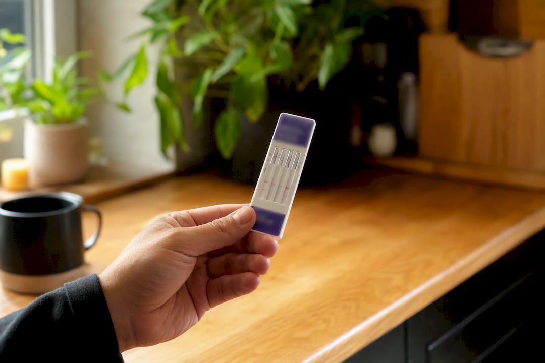Hand holding urine test strip for detox progress