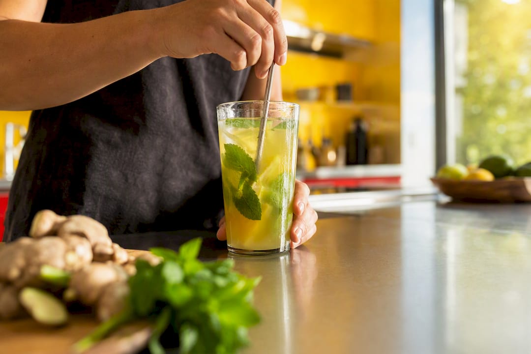 Hands mixing detox drink at kitchen counter