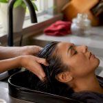 Hands washing hair near scalp at sink