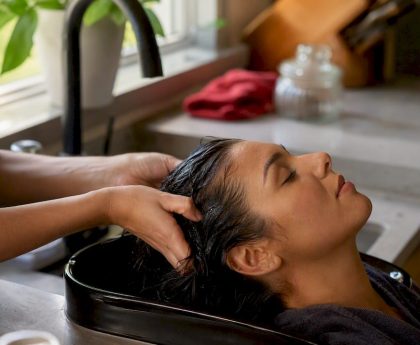 Hands washing hair near scalp at sink