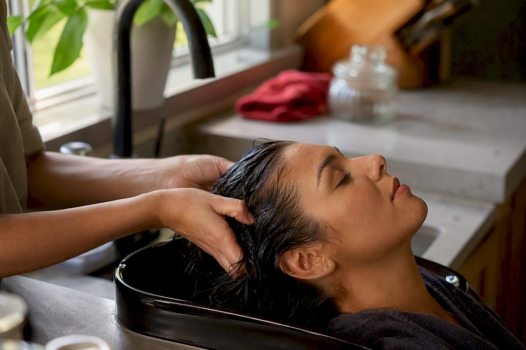 Hands washing hair near scalp at sink