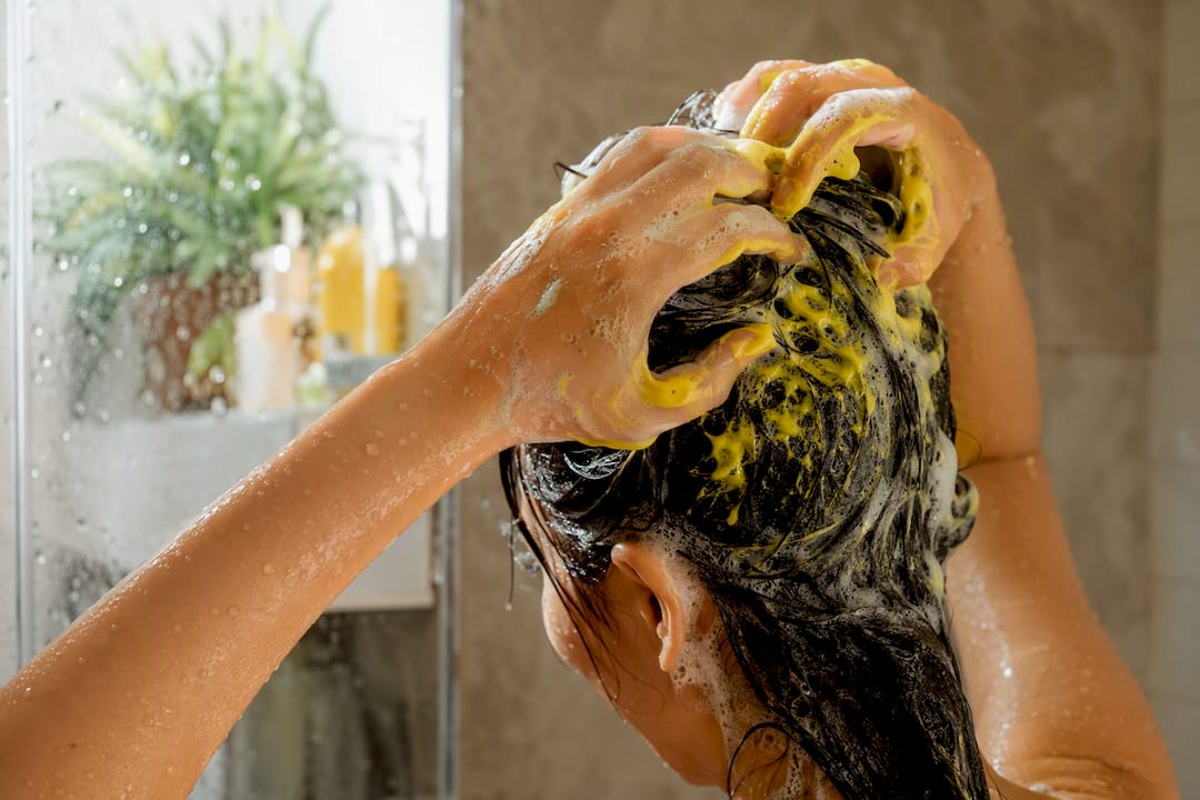 Hands applying shampoo at hair roots