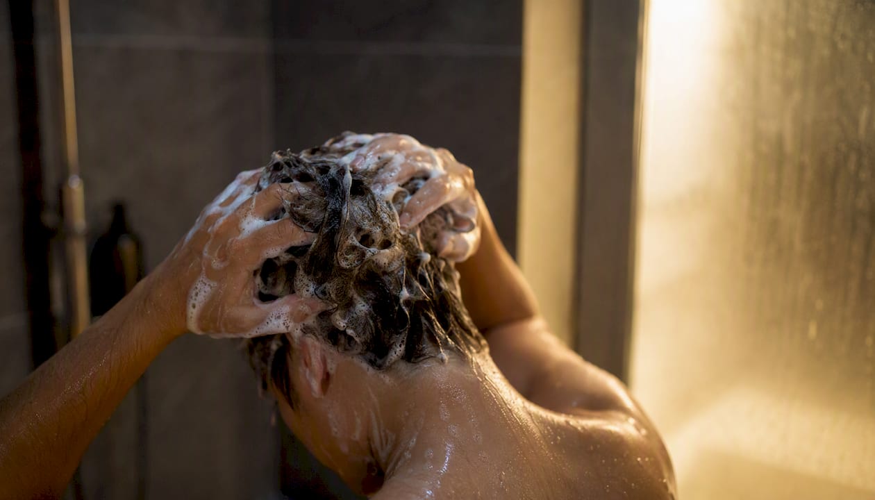 Hands massaging detox shampoo into hair