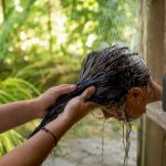 Close-up of hands rinsing hair at sink