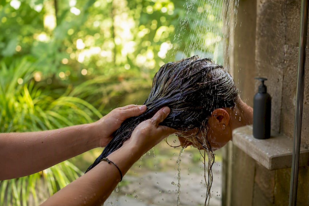 Close-up of hands rinsing hair at sink