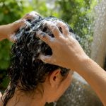 Hands applying detox shampoo to scalp