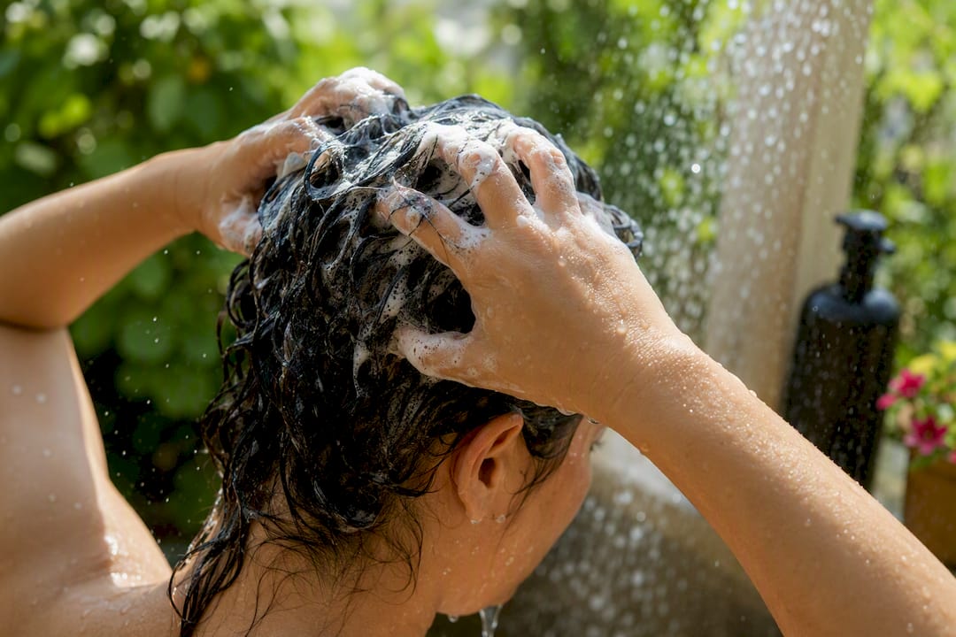 Hands applying detox shampoo to scalp