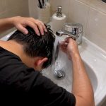 Person rinsing irritated scalp at bathroom sink