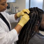 Technician examining dreadlock roots for hair testing