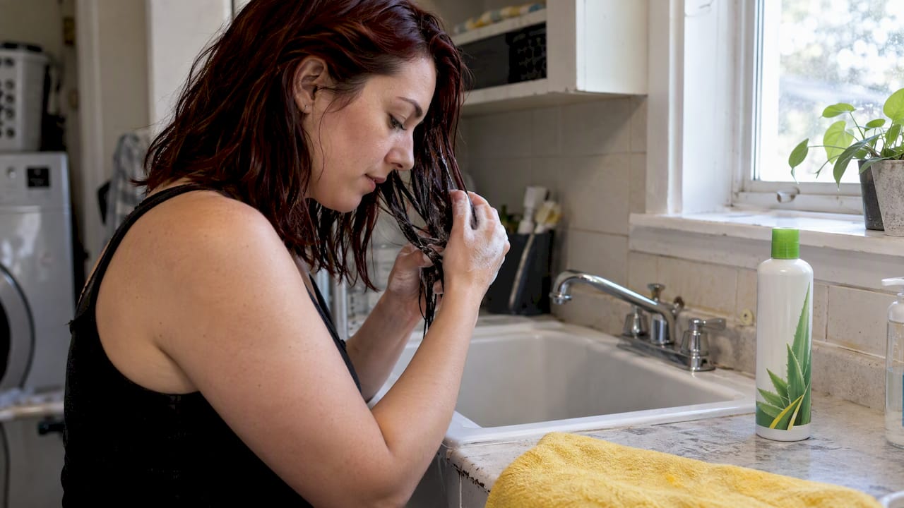 Woman applying detox shampoo to dyed hair