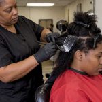 Stylist applying relaxer to sectioned hair