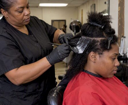Stylist applying relaxer to sectioned hair