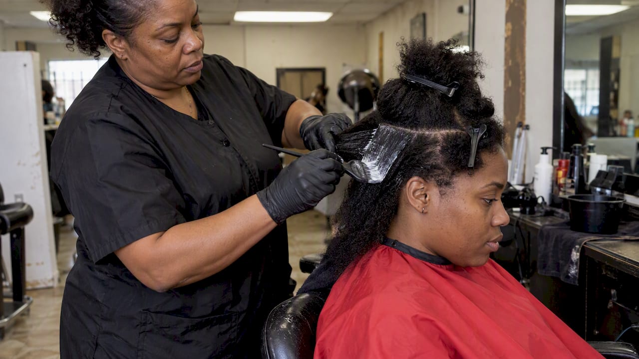Stylist applying relaxer to sectioned hair