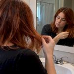 Woman inspecting her color-treated hair in a mirror