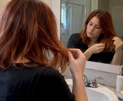 Woman inspecting her color-treated hair in a mirror