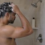 Man shampooing his hair in a shower
