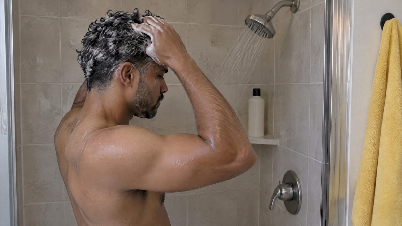 Man shampooing his hair in a shower