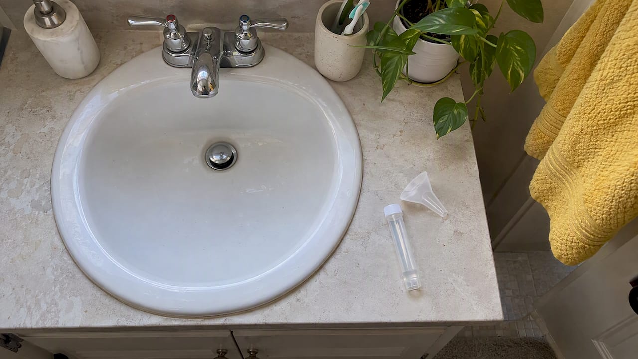 Saliva collection tube and funnel beside a sink